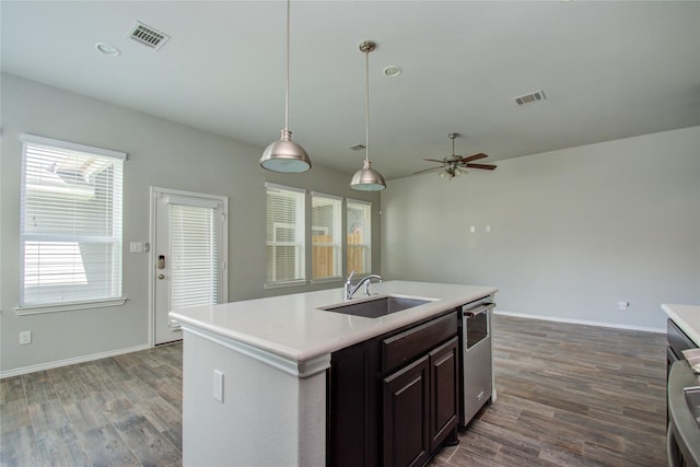 kitchen with a sink, light countertops, dark wood finished floors, and dishwasher