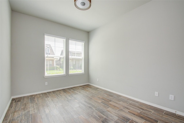 spare room with baseboards and wood finished floors