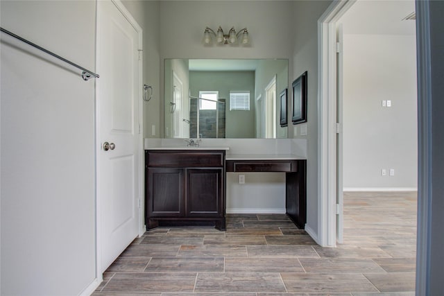 full bath with vanity, baseboards, walk in shower, and wood finished floors