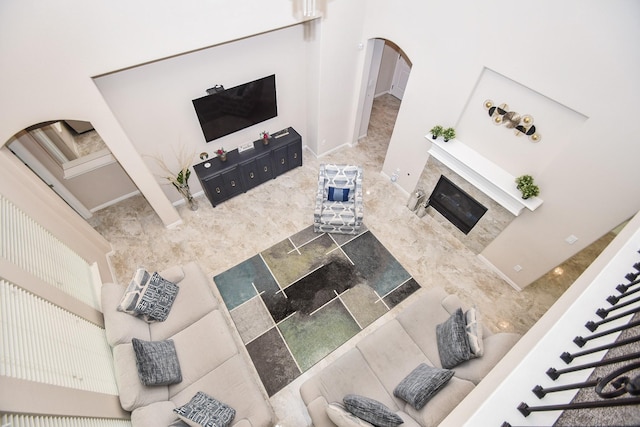 living area with a tiled fireplace and arched walkways