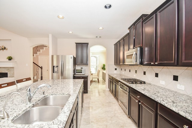 kitchen featuring arched walkways, appliances with stainless steel finishes, a sink, and tasteful backsplash