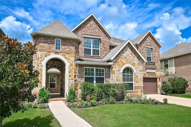 view of front of home featuring driveway, a garage, a front lawn, a shingled roof, and stone siding