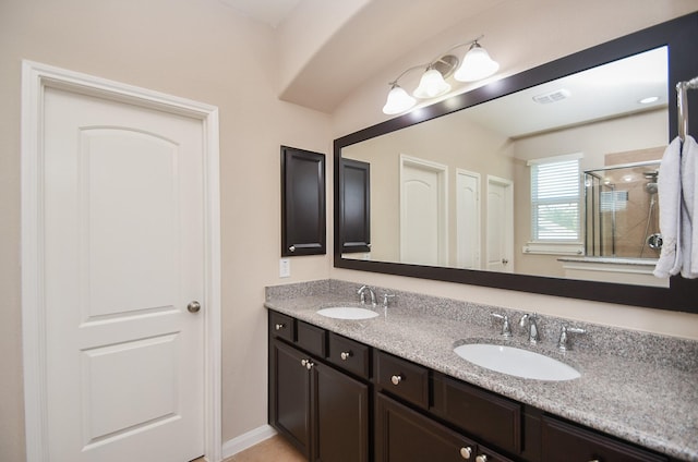 full bathroom with double vanity, a sink, and a stall shower