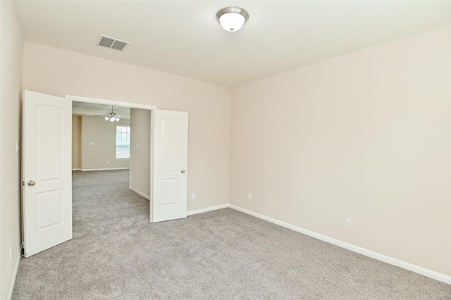 empty room featuring baseboards, light carpet, a ceiling fan, and visible vents