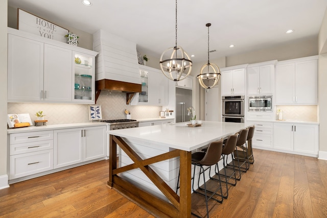 kitchen featuring a kitchen bar, white cabinets, a chandelier, backsplash, and stainless steel appliances