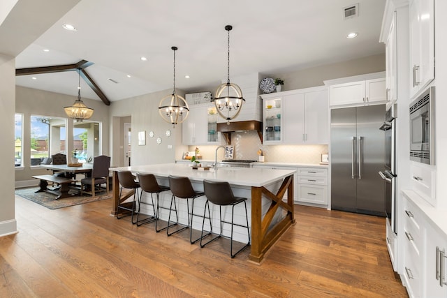 kitchen featuring visible vents, decorative backsplash, an inviting chandelier, built in appliances, and light countertops