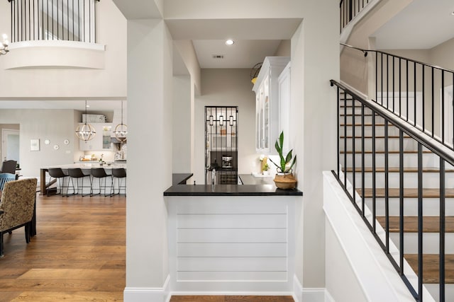 bar featuring visible vents, wood finished floors, stairway, recessed lighting, and a chandelier