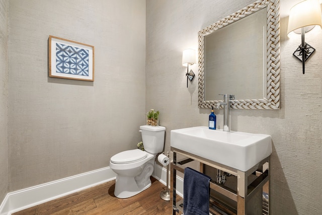 bathroom with baseboards, wood finished floors, and toilet