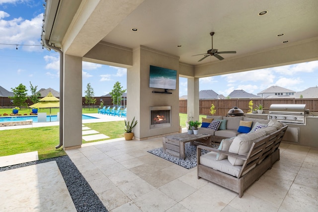 view of patio featuring grilling area, exterior kitchen, an outdoor living space with a fireplace, a fenced in pool, and a fenced backyard