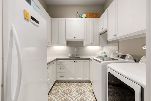 laundry area with cabinet space, separate washer and dryer, and a sink