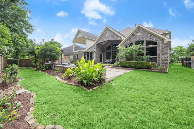 rear view of house with a lawn, brick siding, a patio, and a fenced backyard