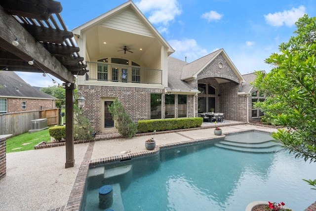 rear view of house with brick siding, central AC unit, a patio area, a balcony, and a ceiling fan