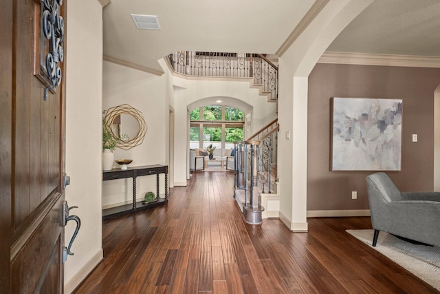 entryway with crown molding, arched walkways, stairway, and visible vents