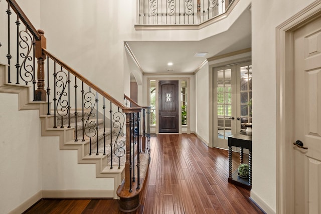 entrance foyer featuring french doors, baseboards, wood finished floors, ornamental molding, and stairway
