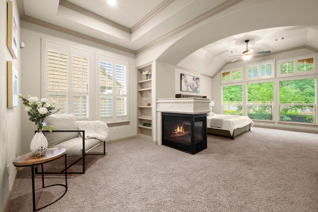 living area featuring built in features, baseboards, ceiling fan, a multi sided fireplace, and carpet