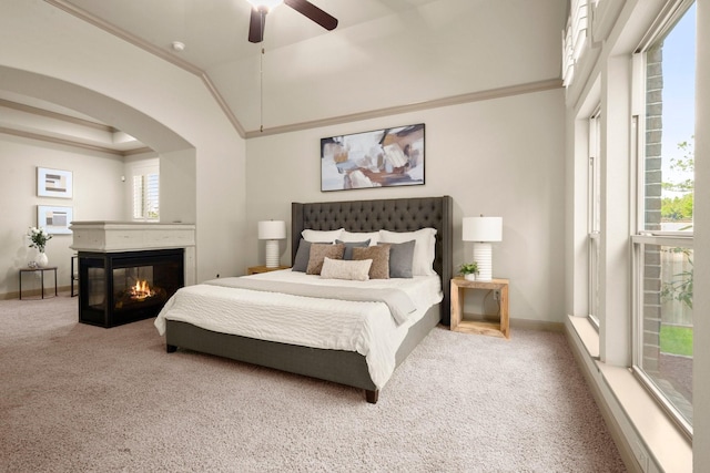 carpeted bedroom with a multi sided fireplace, arched walkways, crown molding, and baseboards