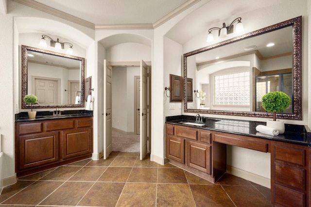 bathroom featuring crown molding, baseboards, two vanities, and a sink