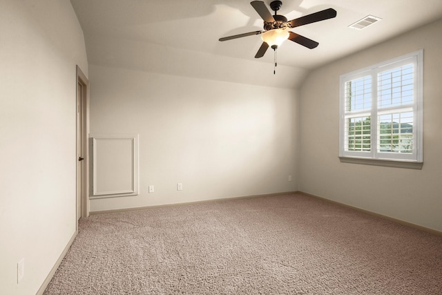 carpeted spare room featuring visible vents, baseboards, ceiling fan, and vaulted ceiling