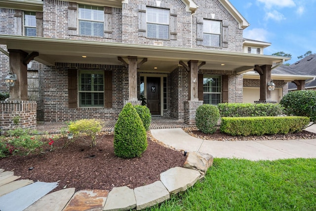 entrance to property featuring a porch and brick siding
