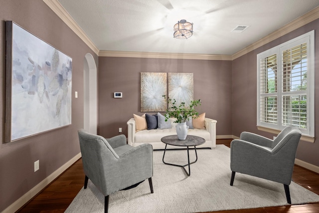 living room with crown molding, arched walkways, baseboards, and wood finished floors