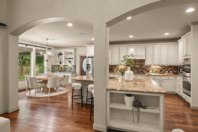 kitchen featuring a center island, open shelves, arched walkways, and tasteful backsplash