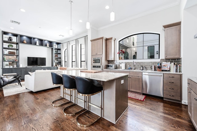 4707 Jackson St, Houston, TX 77004 - kitchen featuring appliances with stainless steel finishes, ornamental molding, a center island, backsplash, and light stone counters