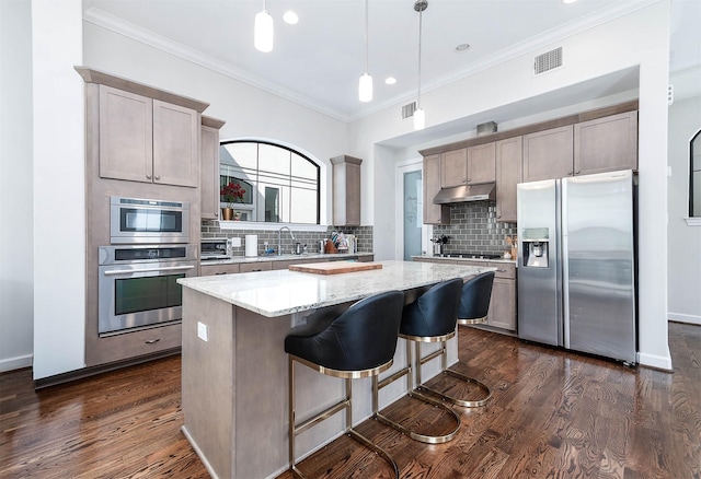 4707 Jackson St, Houston, TX 77004 - kitchen featuring appliances with stainless steel finishes, under cabinet range hood, backsplash, a center island, and crown molding