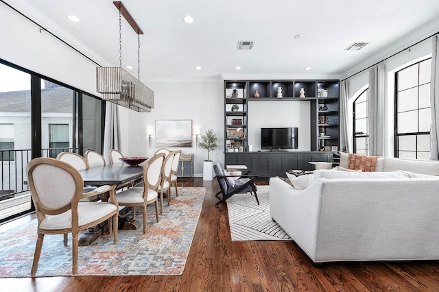 living room with crown molding, dark wood-style flooring, visible vents, and a wealth of natural light