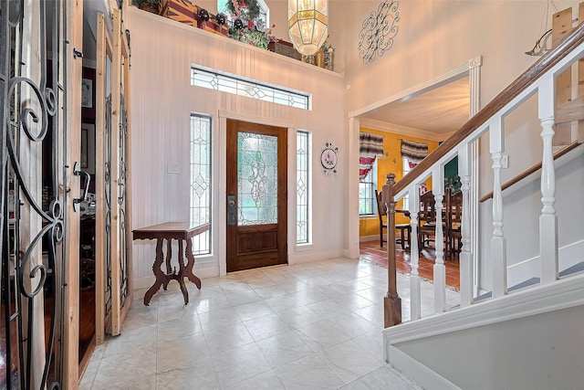 tiled foyer entrance with baseboards and a high ceiling