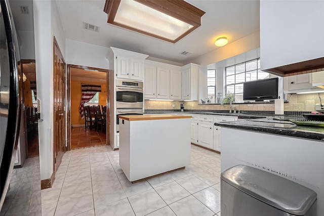 kitchen featuring stainless steel double oven, visible vents, a wealth of natural light, and tasteful backsplash