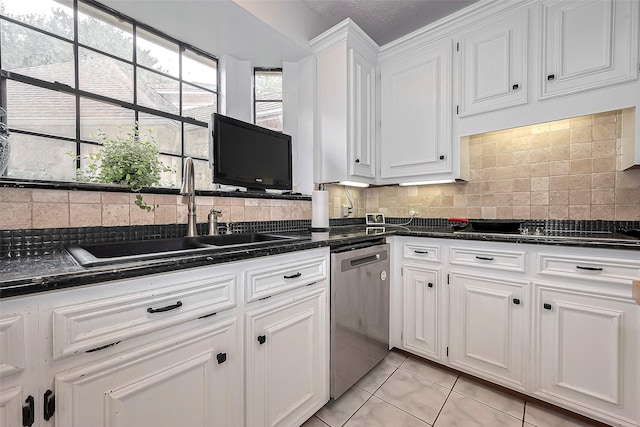 kitchen with a sink, dark countertops, stainless steel dishwasher, and white cabinetry
