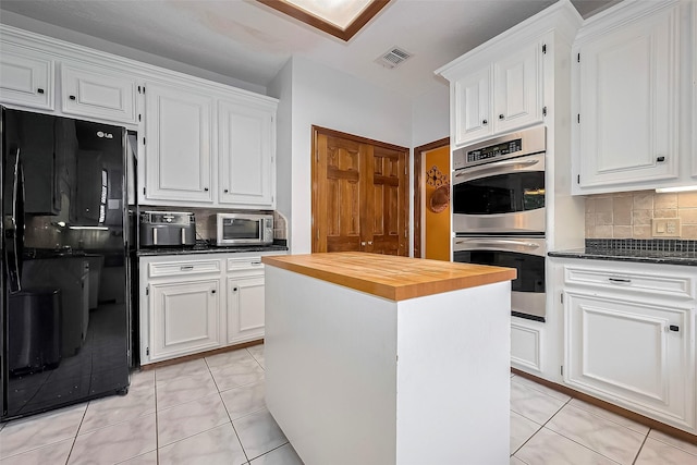 kitchen featuring visible vents, butcher block counters, white cabinetry, appliances with stainless steel finishes, and backsplash
