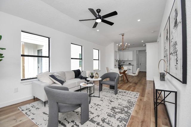 living room featuring recessed lighting, baseboards, ceiling fan with notable chandelier, and light wood-type flooring