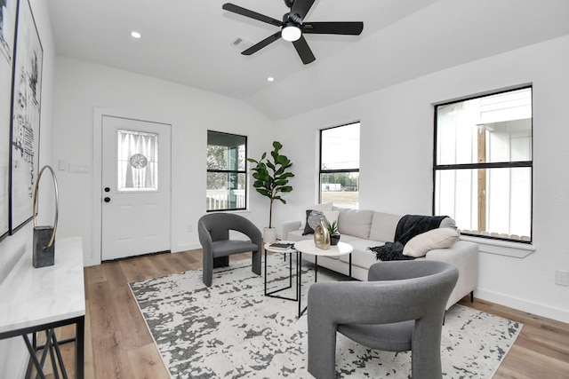 living room featuring visible vents, light wood-style flooring, ceiling fan, and lofted ceiling