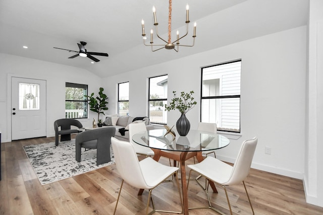 dining area with wood finished floors, baseboards, ceiling fan with notable chandelier, and lofted ceiling