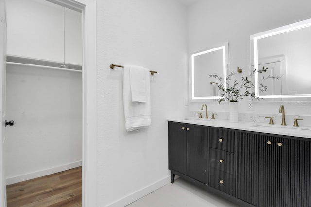 bathroom with baseboards, a sink, and double vanity