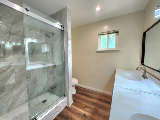 full bathroom featuring toilet, baseboards, wood finished floors, and a stall shower