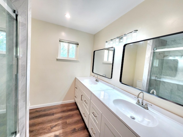 bathroom with double vanity, a shower stall, wood finished floors, a sink, and toilet