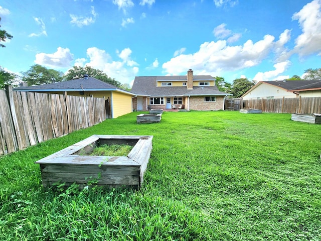 back of house featuring an outdoor fire pit, a vegetable garden, a fenced backyard, a chimney, and a lawn