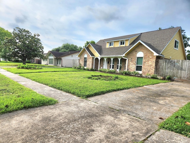 traditional home with fence, a shingled roof, a front yard, and brick siding