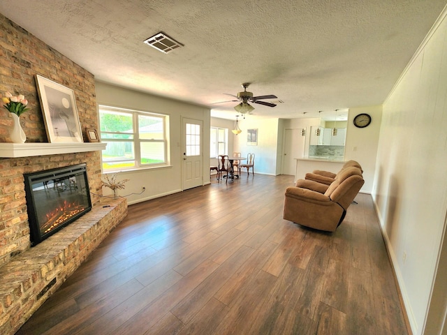 living area featuring ceiling fan, dark wood-style flooring, a textured ceiling, visible vents, and baseboards
