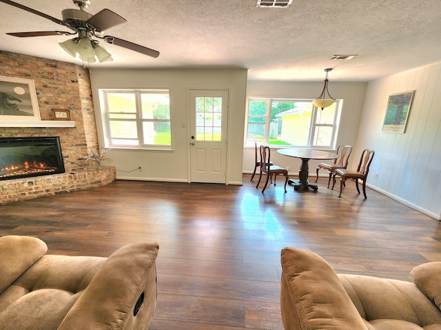 living area with a healthy amount of sunlight, baseboards, dark wood-style floors, and visible vents