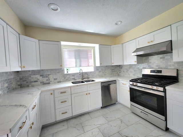 kitchen with appliances with stainless steel finishes, a sink, white cabinets, marble finish floor, and under cabinet range hood
