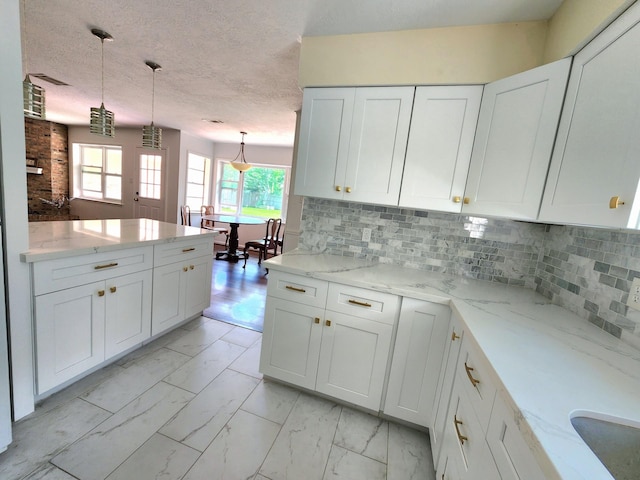 kitchen with pendant lighting, light stone countertops, white cabinetry, and marble finish floor
