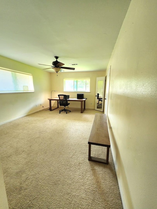 interior space with baseboards, visible vents, a ceiling fan, and light colored carpet