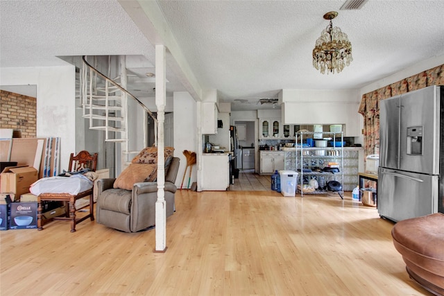 interior space featuring light wood-style floors, a textured ceiling, and stairs