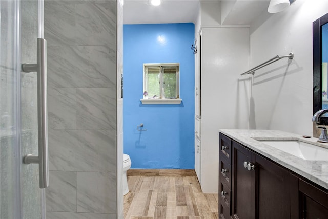 bathroom with vanity, a stall shower, toilet, and wood finished floors
