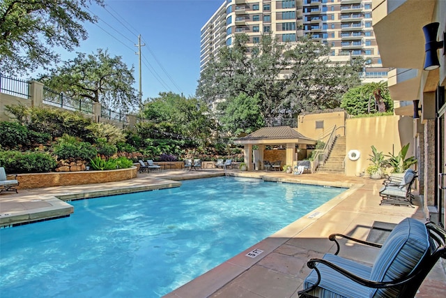 pool with a patio, fence, and a gazebo