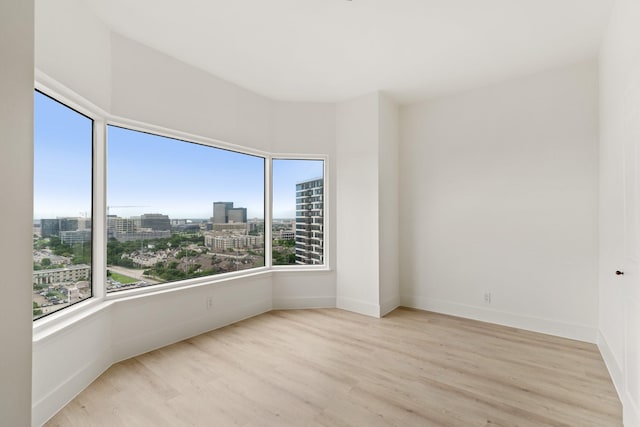 empty room featuring a view of city, baseboards, and wood finished floors