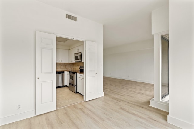 unfurnished living room with light wood-style floors, baseboards, and visible vents